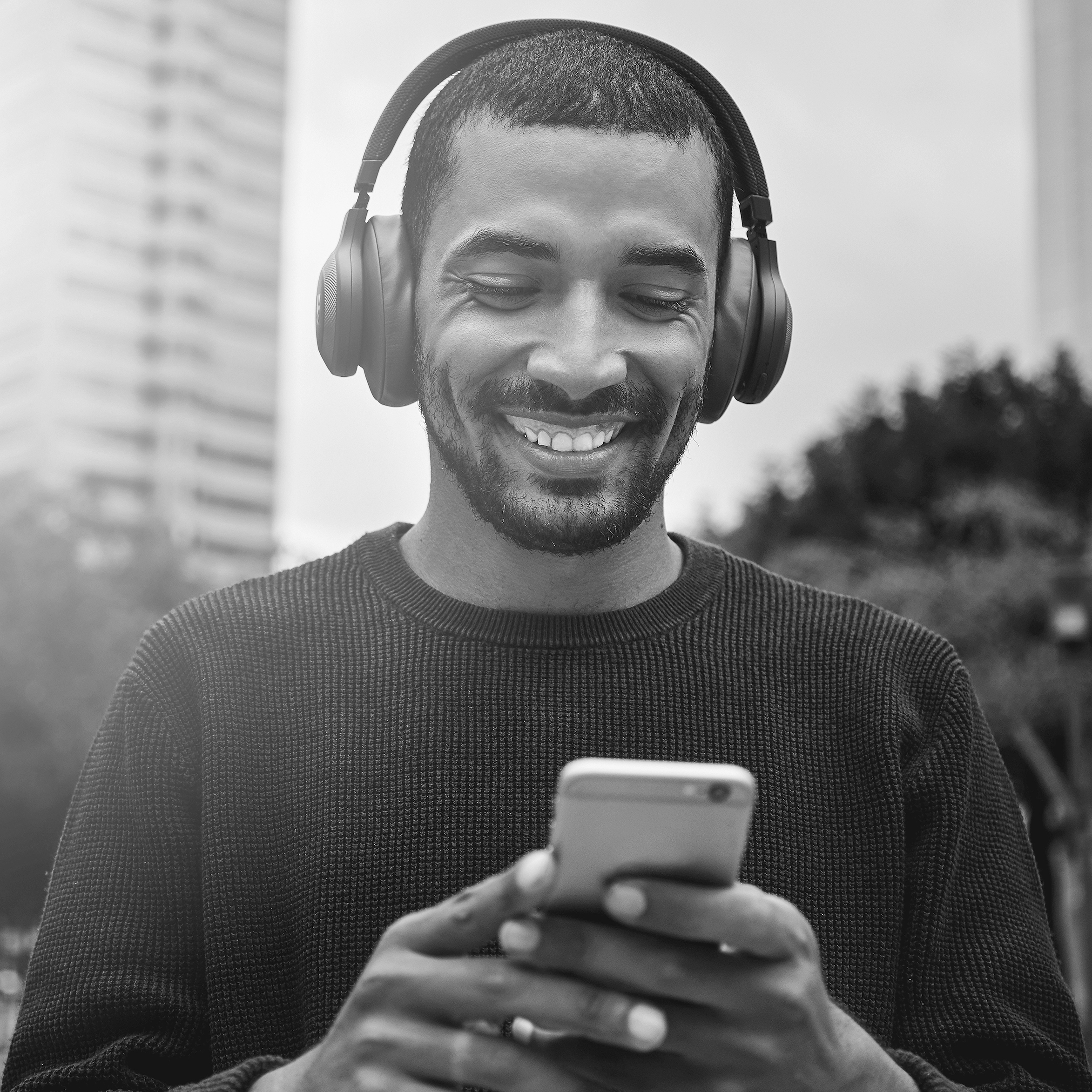 Young,Man,Looking,At,Smartphone,With,Headphone,On,His,Head